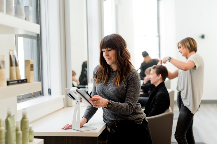 Coiffeuse regarder ses rendez-vous sur tablette dans son salon